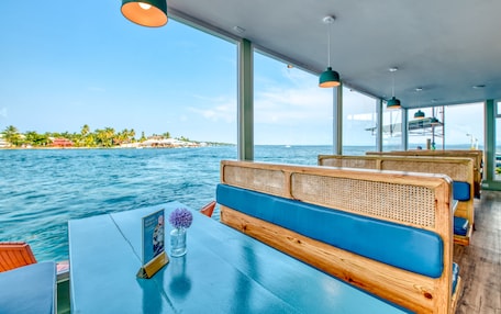 A boat with wooden benches and tables, large windows, and a view of the sea and a distant island.