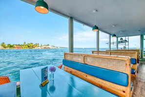A boat with wooden benches and tables, large windows, and a view of the sea and a distant island. - Bocas Paradise Hotel (Bocas del Toro)