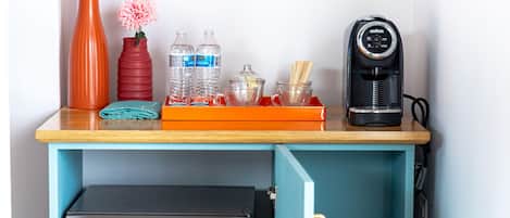 A kitchenette with a coffee maker, water bottles, a vase with flowers, and a Hisense refrigerator.