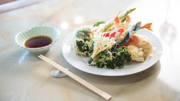 A plate of food with chopsticks and a small bowl of sauce on a table.