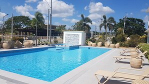 A swimming pool with lounge chairs and a pergola.
