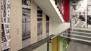 A modern interior with a staircase, glass railings, and patterned wall designs.