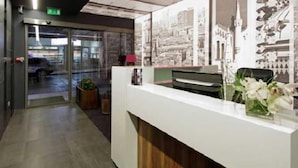 A reception area with a glass door entrance, a reception desk, and a wall with printed images.