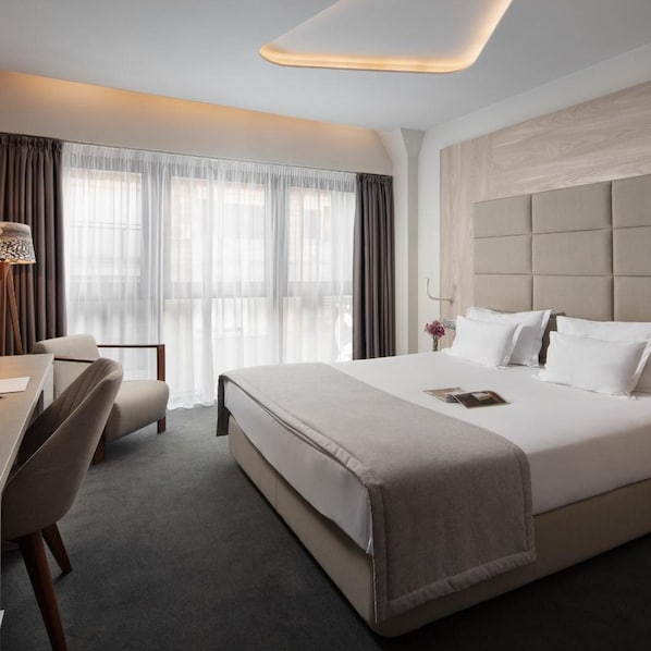 Une chambre d’hôtel avec un grand lit, un bureau et une chaise.