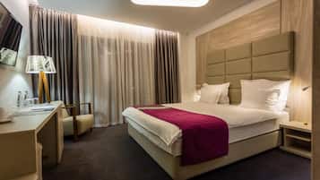 Une chambre d’hôtel avec un lit, une table de chevet, une lampe, une chaise et des rideaux.
