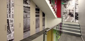 Um interior moderno com escada, guarda-corpos de vidro e design de parede estampado.