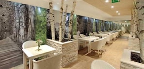A restaurant with birch tree murals, white chairs, and a stone counter. - Colors Inn (Sarajevo)