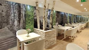A restaurant with birch tree murals, white chairs, and a stone counter.