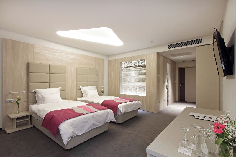Une chambre d’hôtel avec deux lits, un bureau, une télévision et une fenêtre donnant sur un beau paysage.