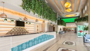 A hotel reception area with a modern design, including a reception desk, a large screen, and a green-lit corridor. - Ramada by Wyndham Usak (Usak)