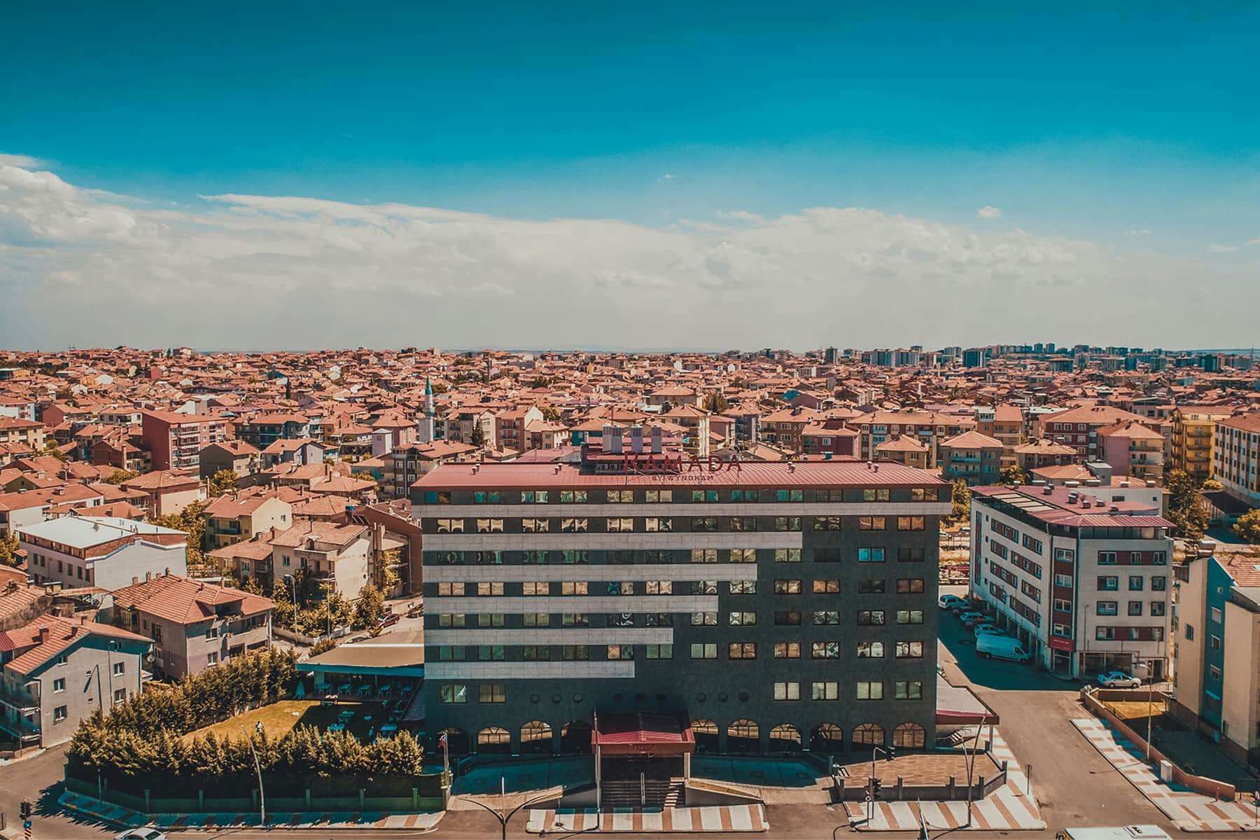 Un edificio de varios pisos con techo plano, rodeado de una zona urbana densa con edificios de baja altura.