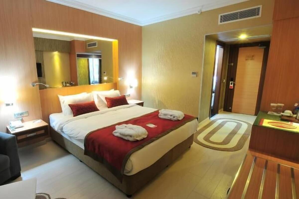 A hotel room with a bed, a chair, a desk, and a bathroom door.