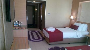 A hotel room with two beds, a desk, a TV, and a bathroom visible through an open door.