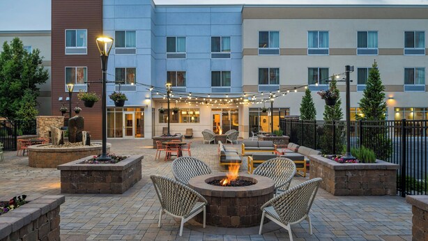 A courtyard with outdoor seating, a fire pit, and string lights.