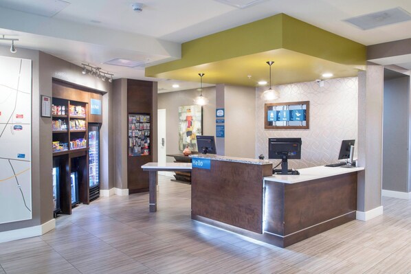A reception area with a reception desk, a vending machine, and a wall-mounted information board.