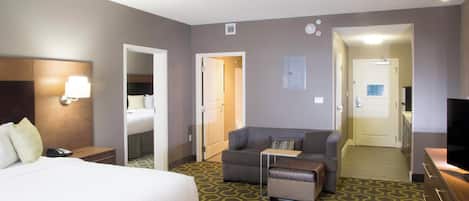 Una camera d'albergo con un letto, un divano, una televisione e una scrivania.