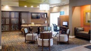 A hotel lobby with a reception desk, seating area, and a computer station. - TownePlace Suites Oxford (Oxford)