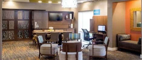 A hotel lobby with a reception desk, seating area, and a computer station.