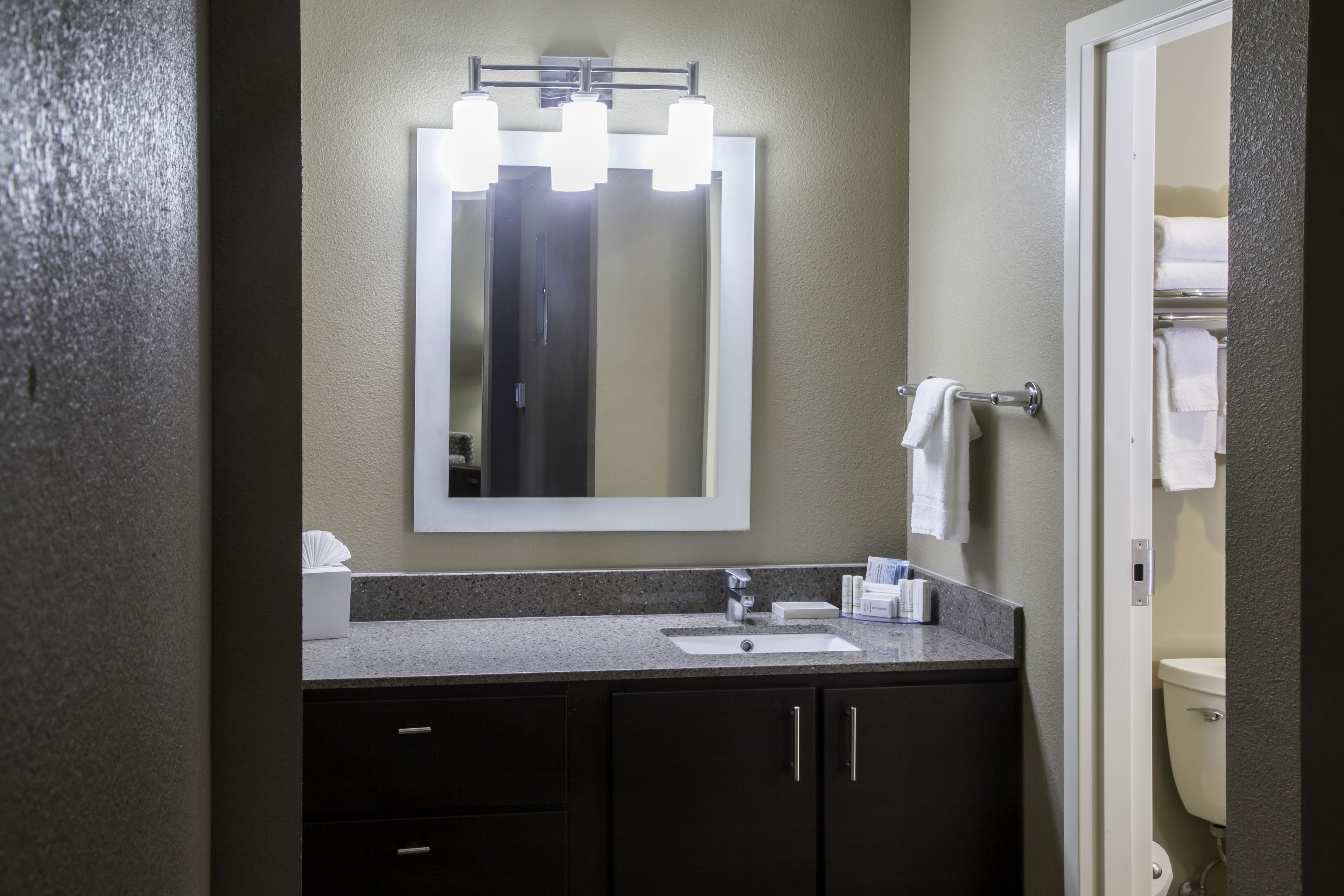 A bathroom with a sink, mirror, and towel rack.