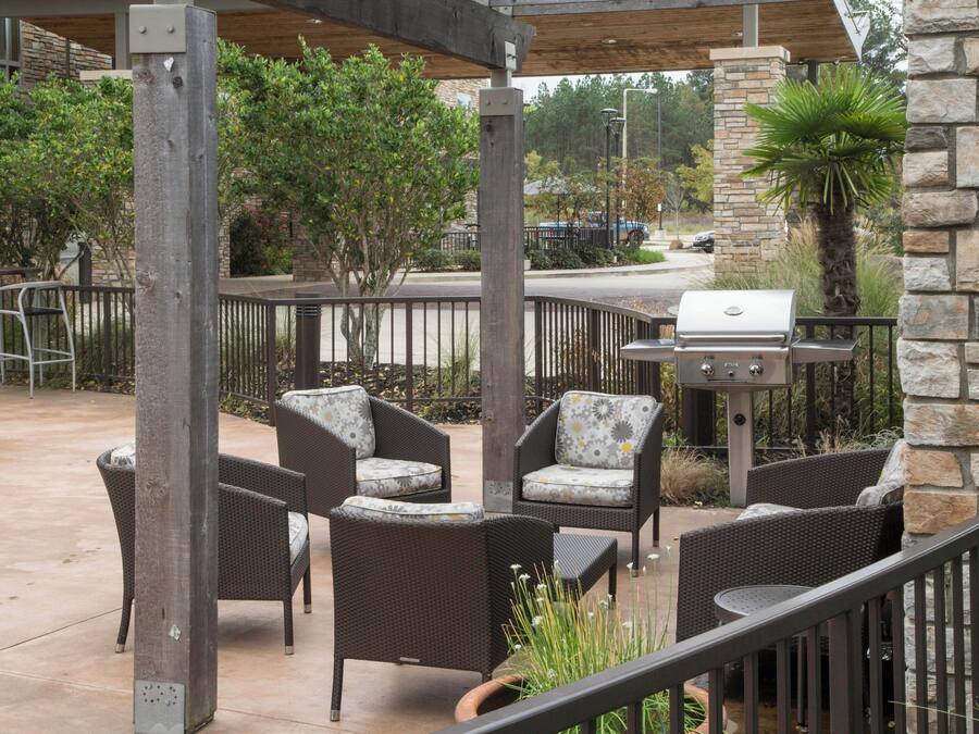 Un patio al aire libre con mobiliario de mimbre, una parrilla y pilares de piedra.