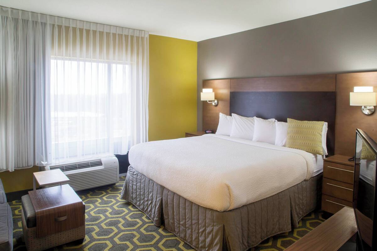 Habitación de hotel con una cama grande, lámparas de noche, un escritorio y una silla.