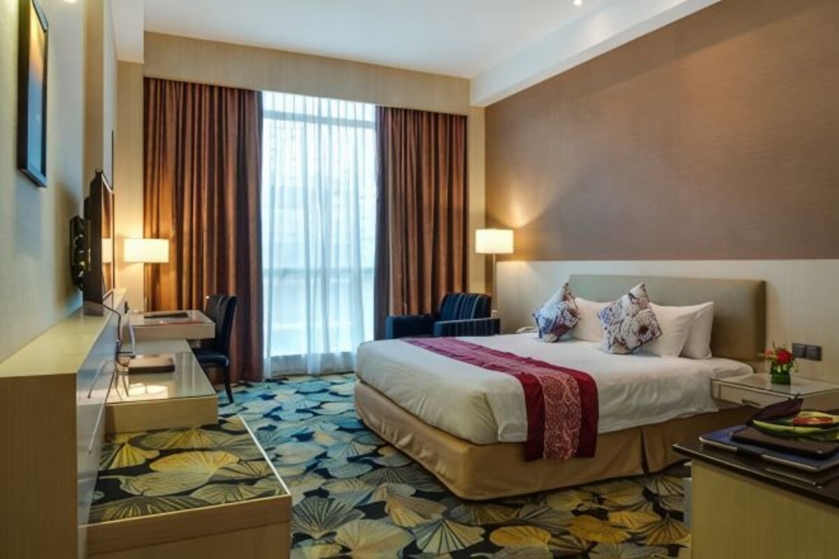 Habitación de hotel con cama, escritorio, silla y vistas al exterior.