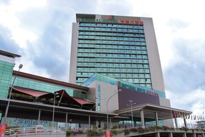 Un hotel con fachada de vidrio moderna, varios pisos y un letrero llamativo.