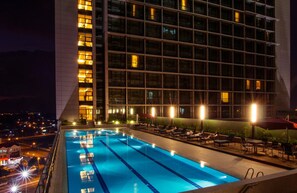 A rooftop pool with lounge chairs and umbrellas, surrounded by a modern building with illuminated windows. - Imperial Hotel Kuching (Kuching)
