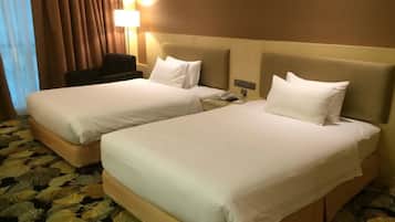 Quarto de hotel com duas camas, uma escrivaninha, uma lâmpada e um telefone.