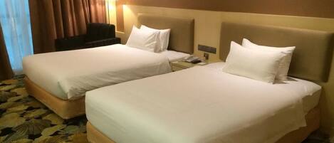 A hotel room with two beds, a desk, a lamp, and a telephone.