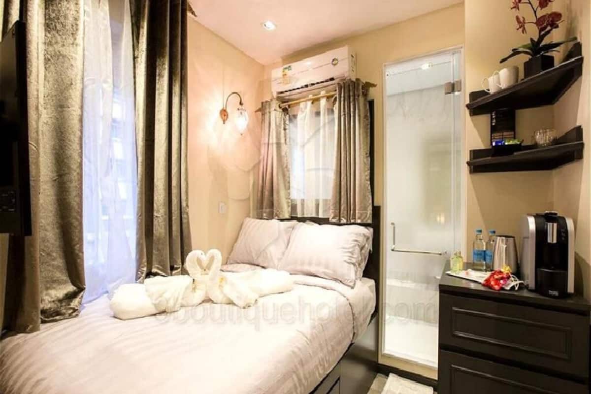 A hotel room with a bed, a desk, a shower, and a shelf with toiletries.