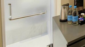 A bathroom with a frosted glass door, a towel rack, and a shelf with bottles and glasses. - 9 Boutique Hotel (Hong Kong)