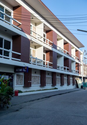 A multi-story building with a ground-level ATM, a balcony on the second floor, and a red brick facade. - Phangan Pearl Villa (Ko Pha-ngan)