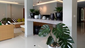 Una sala de estar moderna con un sofá, una mesa de centro y un comedor con barra y plantas en macetas.