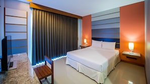 Una habitación de hotel moderna con una cama grande, mesitas de noche, un escritorio y un televisor.