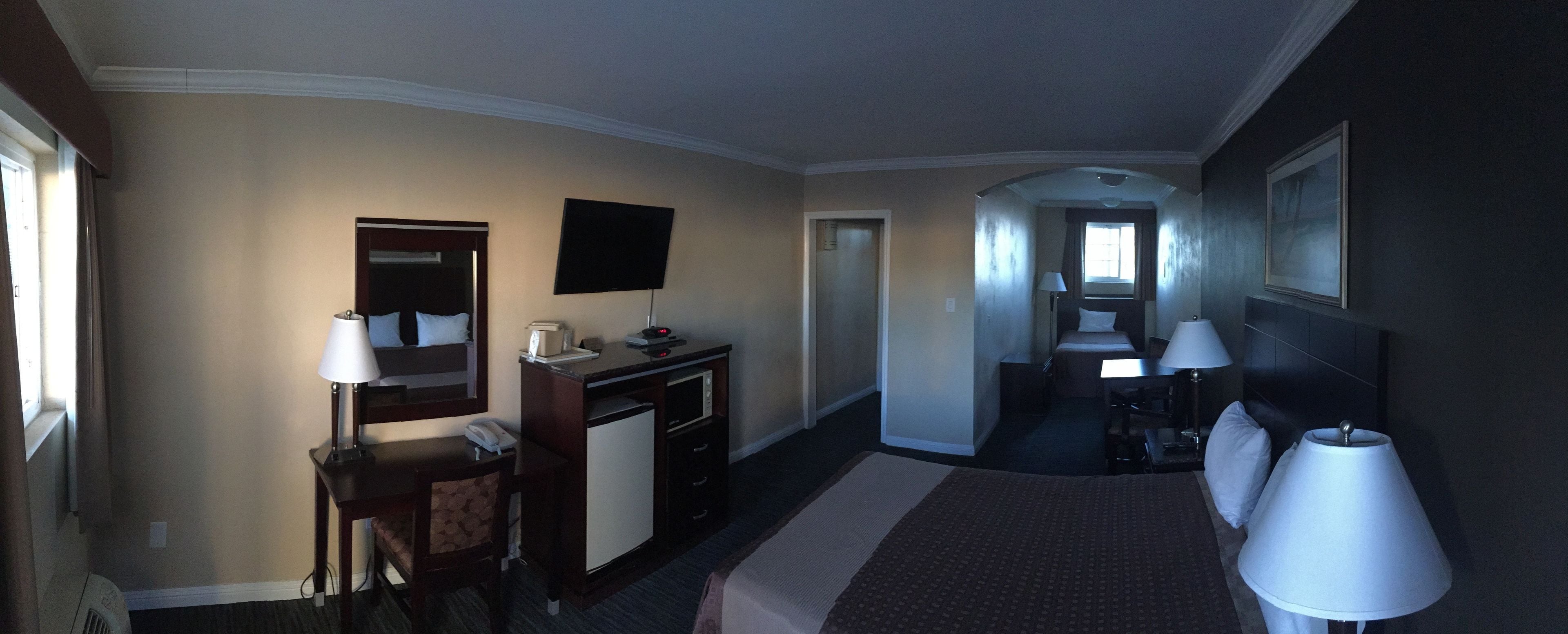 Een hotelkamer met een bed, bureau, stoel, bureaulamp en een televisie aan de muur.