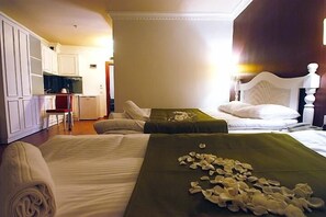 A hotel room with two beds, a kitchenette, and a bathroom.