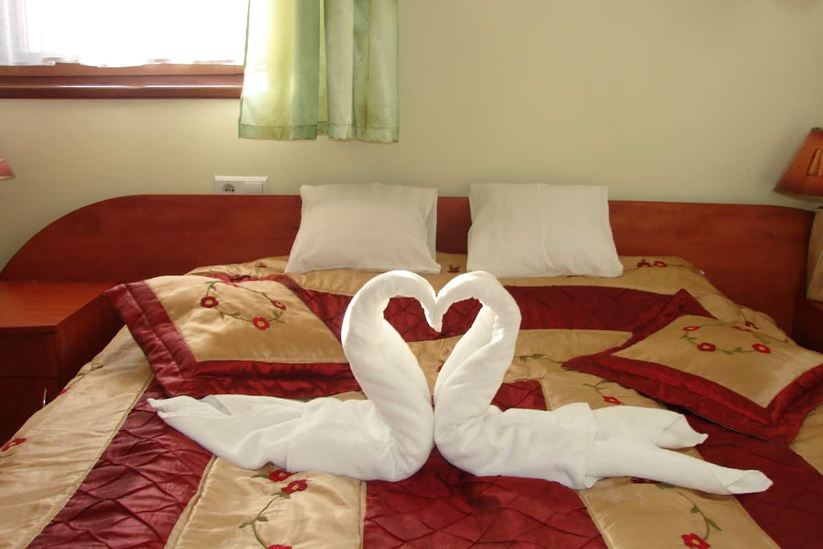 Ein Bett mit einer herzförmigen Handtuchanordnung und floralem Bettbezug.