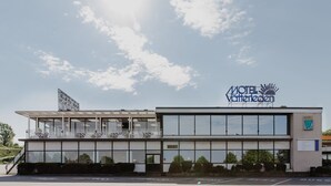 Un motel moderno con un cartel llamativo, ventanas amplias y un área exterior cubierta.