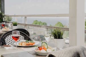Una mesa de comedor con platos de comida, copas de vino tinto y blanco, y una planta en maceta.