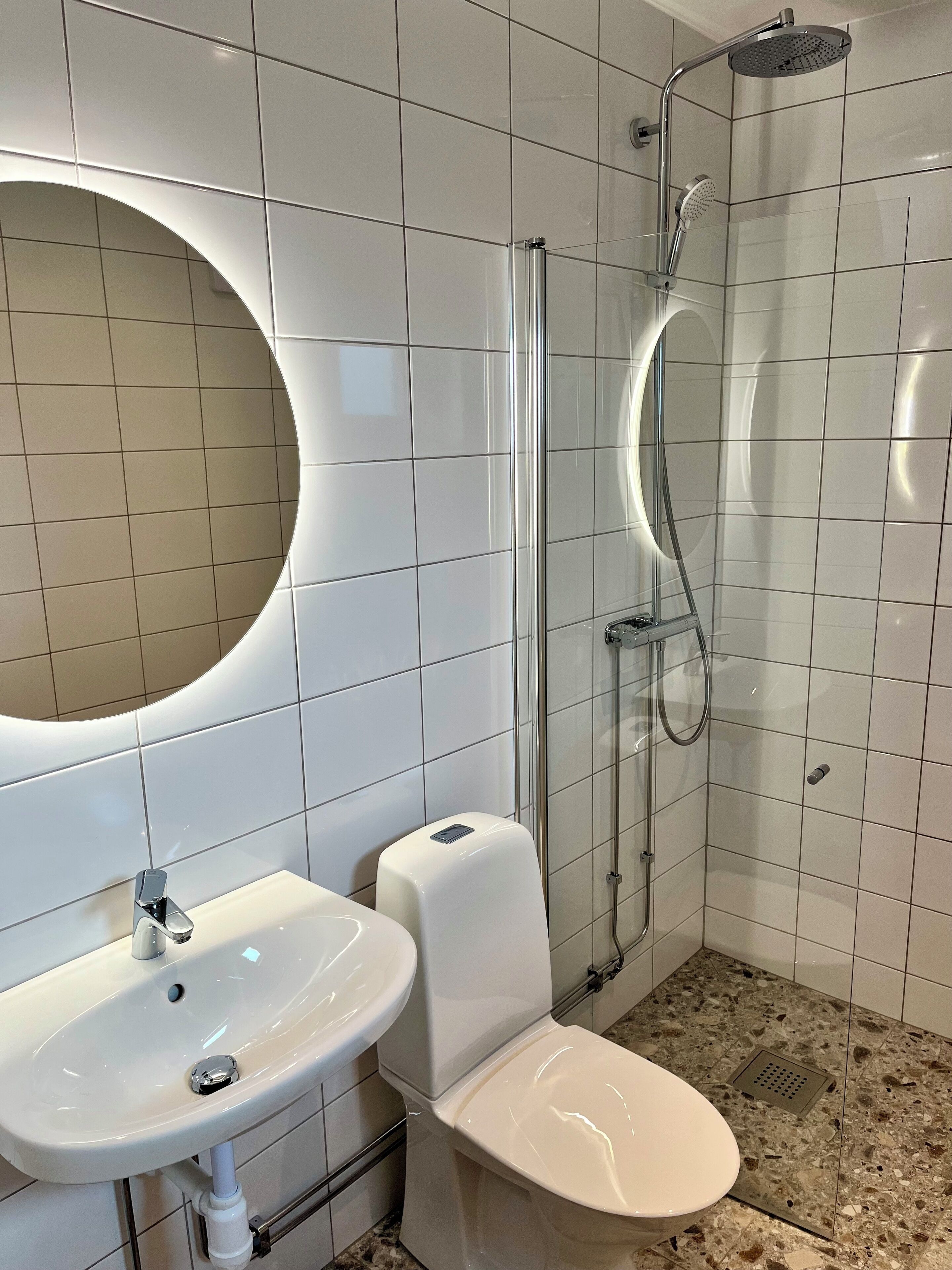 Un baño moderno con lavamanos, inodoro y ducha blancos.