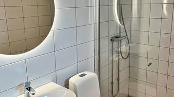 Un baño moderno con lavamanos, inodoro y ducha blancos.