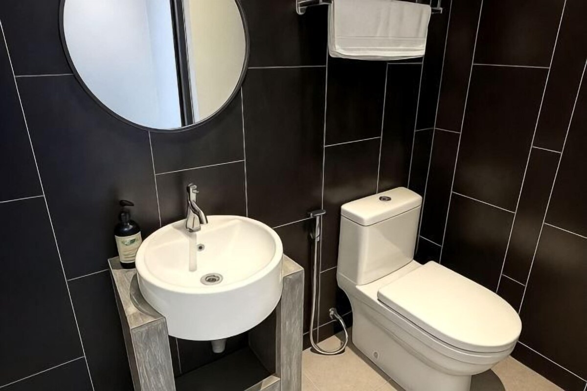 A modern bathroom with a white sink, toilet, and mirror.