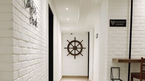 A hallway with white brick walls, a wooden chair, a small table, and a sign reading "Internet Lounge". - Hotel 1915 Kuala Lumpur (Kuala Lumpur)