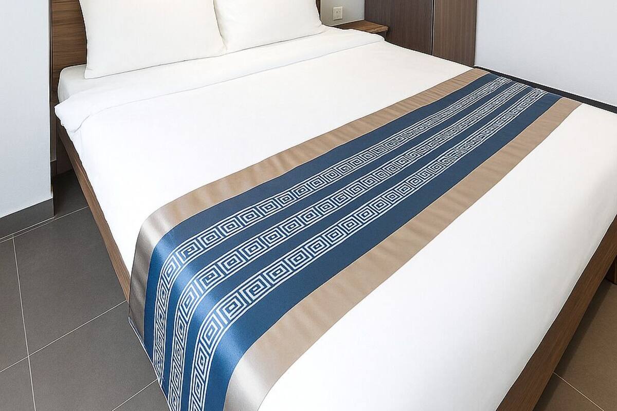 A modern hotel room with a large bed, a wardrobe, and a nightstand.