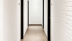 A corridor with white brick walls, black doors, and a tiled floor. - Hotel 1915 Kuala Lumpur (Kuala Lumpur)