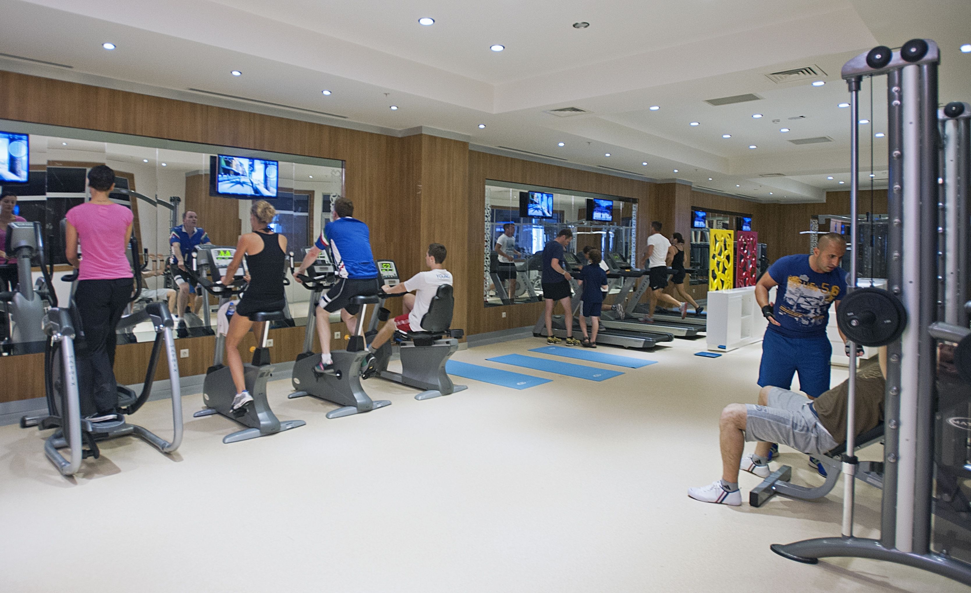 A gym with various exercise equipment, mirrors, and treadmills.