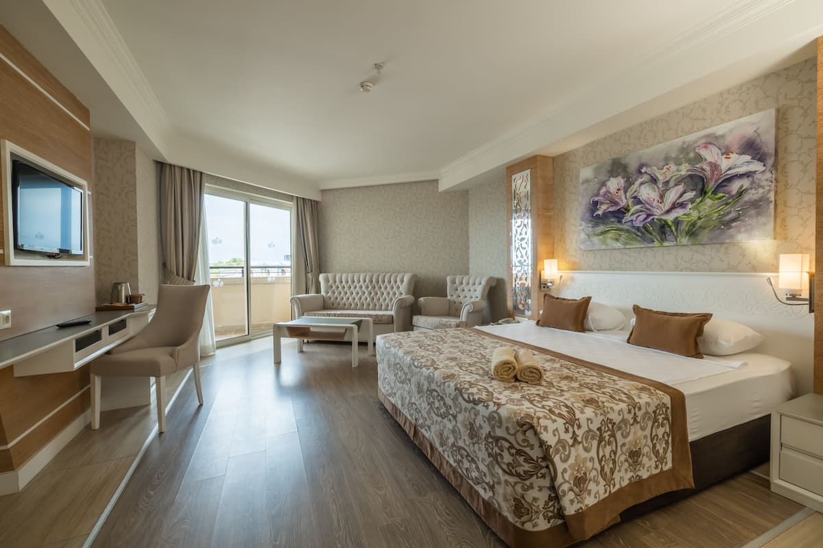 A hotel room with a large bed, a sofa, a desk, and a TV.