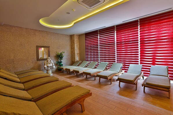 A spa area with multiple lounge chairs, a statue, and red blinds on the windows. - Crystal Sunset Pearl Collection - All inclusive (Manavgat)