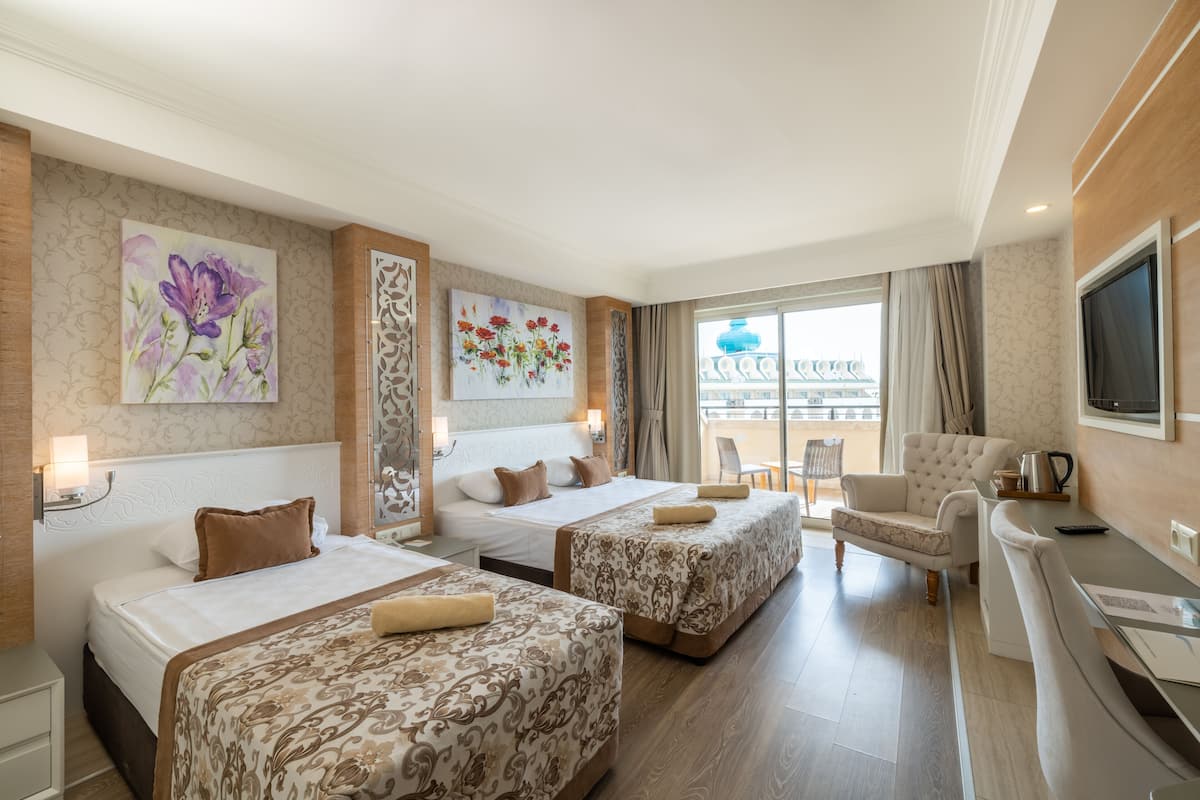 A hotel room with two beds, a desk, a chair, and artwork on the walls.